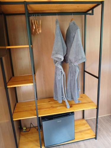 a book shelf with two jackets and a microwave at Vibe Coffee Container CATUAÍ VERMELHO in Pedra Menina