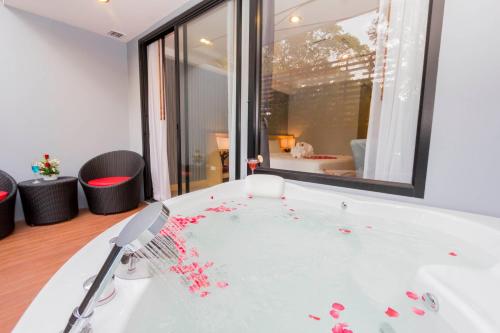 a white bath tub with red petals on it at Apple A Day Resort Krabi, Ao Nang Beach in Ao Nang Beach