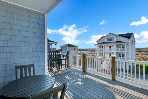 a balcony with a wooden table and chairs on it at Sunset Tide by Sea Scape Properties in North Topsail Beach