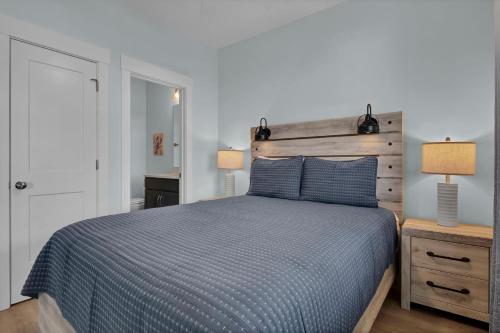 a bedroom with a bed with a blue comforter and two lamps at Sunset Tide by Sea Scape Properties in North Topsail Beach