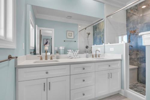 a white bathroom with two sinks and a shower at Sandpipers and Sunshine by Sea Scape Properties in North Topsail Beach