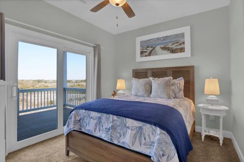a bedroom with a bed and a balcony at Sandpipers and Sunshine by Sea Scape Properties in North Topsail Beach