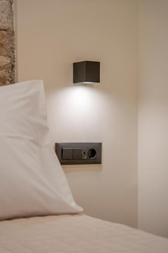 a bed with a pillow and a light on the wall at Casa Myrtēssa in Myrtos