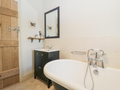 a bathroom with a white sink and a tub and a mirror at White Haywood Barn in Hereford
