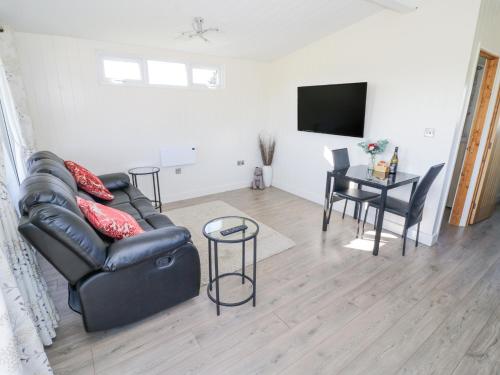 a living room with a black leather couch and a table at Cotswold View 2 in Evesham