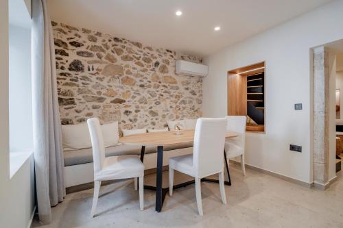 a dining room with a wooden table and white chairs at Casa Myrtēssa in Myrtos