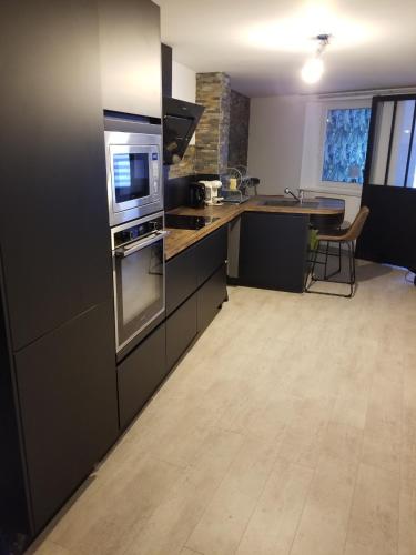 une cuisine avec des appareils en acier inoxydable et une table dans l'établissement Bel appartement avec Balnéo, à Sainte-Marie-aux-Mines