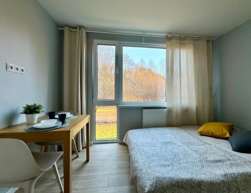 a bedroom with a bed and a table and a window at K22 Park Mokotow Aparts in Warsaw