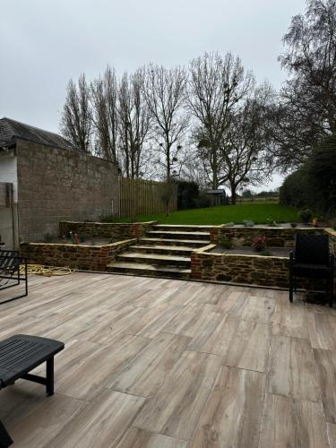 a patio with stairs and a bench and some trees at Maison cosy proche Cancale et Mont-Saint-Michel in Saint-Méloir-des-Ondes