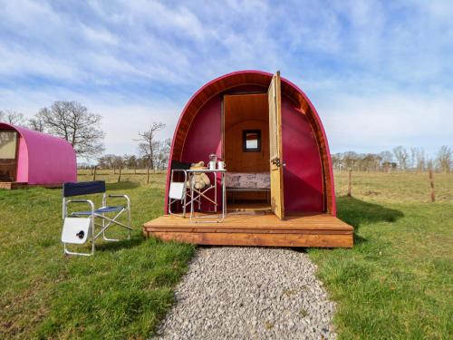 a small tent with a table and a chair in a field at Pod 1 in St Asaph