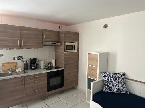 une petite cuisine avec des placards en bois et un canapé dans l'établissement Agréable studio saint Malo, à Saint-Malo