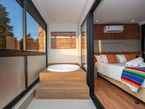 a bedroom with a tub and a bed and a window at Wanderlust Experience Hotel, BW Signature Collection in Campos do Jordão