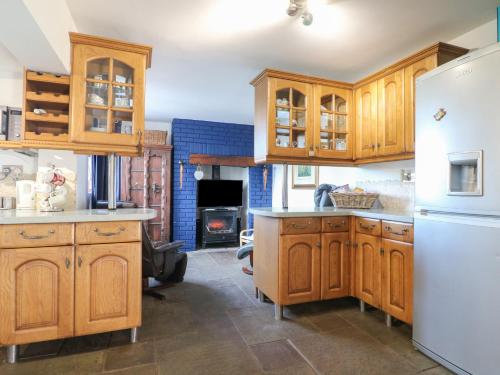 a kitchen with wooden cabinets and a white refrigerator at Woodpit Cottage in Nottingham
