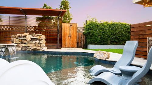 a swimming pool with two chairs in a backyard at Dreamy Lux Heated Pool SPA 3BR in Urban Campbell in Campbell