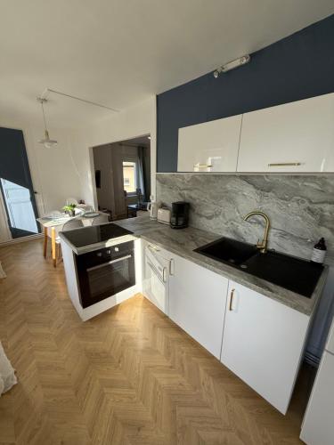 une cuisine avec des armoires blanches et un évier dans l'établissement La Capitainerie - Duplex 2 chambres et coin nuit à 5min à pied de Nausicaa, plage, centre Ville - Côte d'Opale, à Boulogne-sur-Mer
