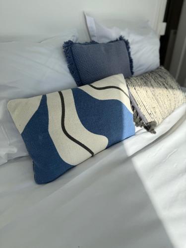 un lit avec des oreillers bleus et blancs dessus dans l'établissement La Capitainerie - Duplex 2 chambres et coin nuit à 5min à pied de Nausicaa, plage, centre Ville - Côte d'Opale, à Boulogne-sur-Mer