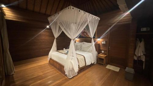 a bedroom with a bed with a mosquito net at Gedong Nusa Huts in Nusa Lembongan
