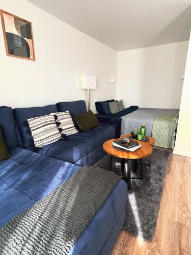 a living room with a blue couch and a table at Forest Studio in Druskininkai