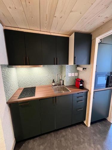 une cuisine avec des armoires vertes et un évier dans l'établissement Résidence Sefcotel - Studio pour 4 Personnes 574, à Tignes