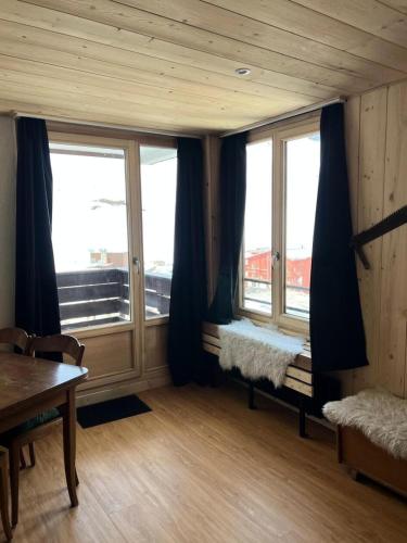 Cette chambre dispose de deux fenêtres, d'une table et d'un banc. dans l'établissement Résidence Sefcotel - Studio pour 4 Personnes 574, à Tignes