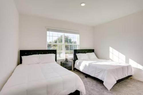 two beds in a bedroom with white walls and a window at Sunset Harem Hideaway Port St Lucie in Port Saint Lucie
