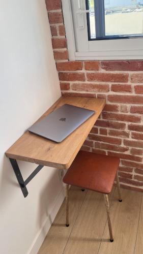 un ordinateur portable assis sur une table en bois à côté d'un mur de briques dans l'établissement Studio 3étoiles à 10 min du Centre - Calme, à Cannes