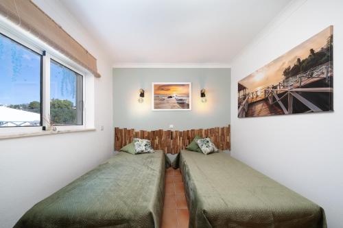 two beds in a room with two windows at Casa Paraiso - stylish gateway in Carvoeiro