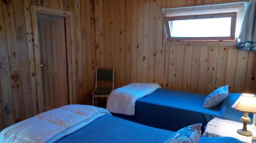 two beds in a wooden room with a window at Casa Oceania del Polonio in Rincón de los Oliveras
