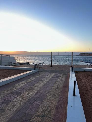 a bench on the beach with the ocean in the background at فندق حياة حقل الفندقية Hayat Haql Hotel in Al Humaizah