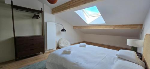 - une chambre avec un grand lit blanc et une lucarne dans l'établissement Au Beau Séjour, à Samoëns