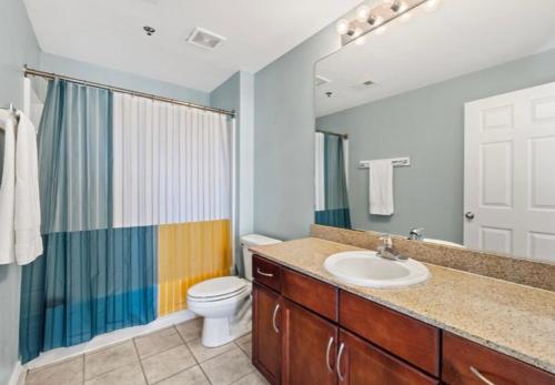 a bathroom with a sink and a toilet and a mirror at BeachFrnt 2 Hottub 5 Pools Jet Ski in Panama City Beach