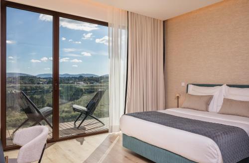a bedroom with a bed and a balcony with a view at Haven Nature Hotel & Villas in Batalha