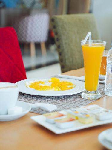 a table with a plate of eggs and a glass of orange juice at Fyndy Hotel Dakhla in Dakhla