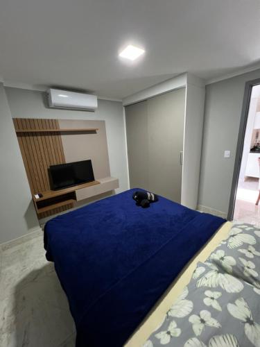 ein Schlafzimmer mit einem blauen Bett und einem TV in der Unterkunft Flat de alto padrão ar condicionado piscina e academia in Campina Grande
