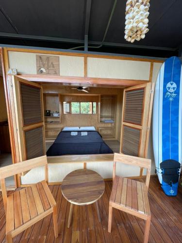 a bedroom with a bed and two chairs and a surfboard at Marena Surf Shack - Casa Akaw in La Salada