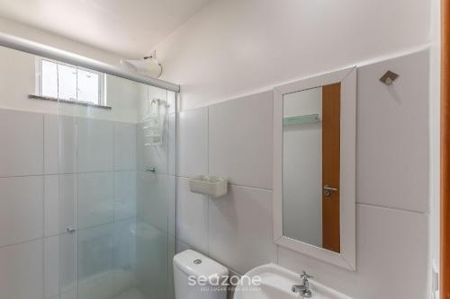 a white bathroom with a mirror and a sink at Apto 450m da Praia em Cond. c/ Piscina VAR0302 in Cururupe
