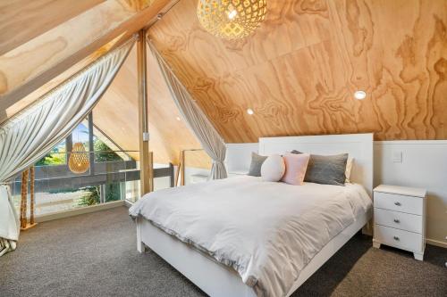 a bedroom with a white bed and a wooden ceiling at The Cabin - Holiday home in Wellington