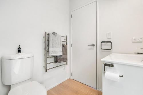 a white bathroom with a toilet and a sink at The Cabin - Holiday home in Wellington