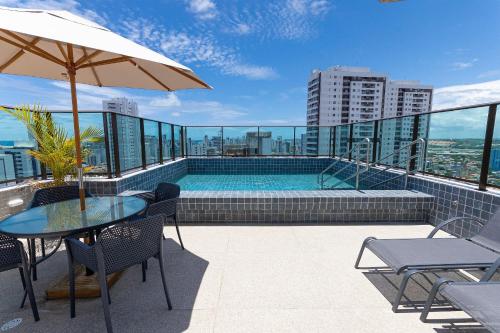 a patio with a table and an umbrella and a pool at Allure Residence by Carpediem in Recife