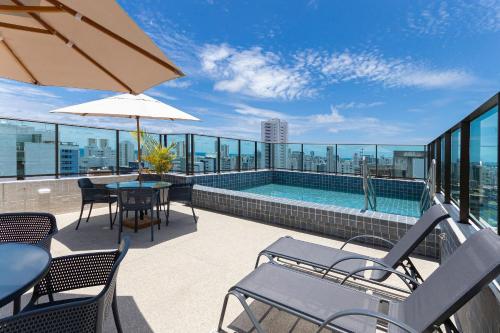 a balcony with a pool and tables and chairs at Allure Residence by Carpediem in Recife