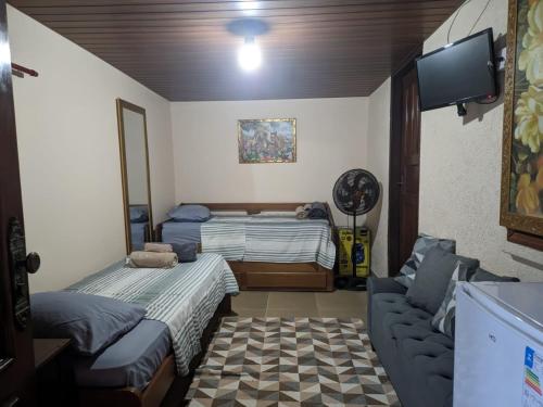 a living room with two beds and a couch at Área de Lazer com quartos e cozinha aberta na Chácara Refrigerio in Salto