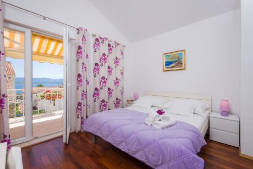 ボルにあるApartments Nadaのベッドルーム1室(紫のシーツが敷かれたベッド1台、窓付)