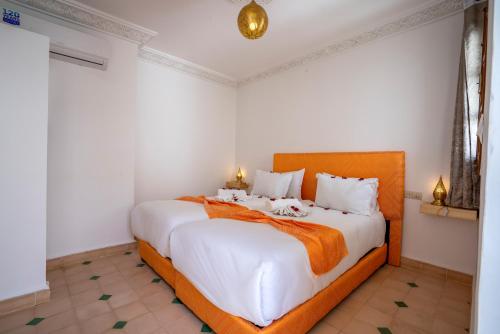 a bedroom with a large white bed with an orange headboard at Riad Ilyan & Spa in Marrakech