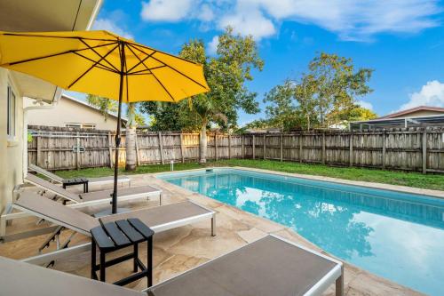 a pool with chairs and an umbrella next to a fence at 4BR with Private Pool and Game Room - Prime Location in Fort Lauderdale