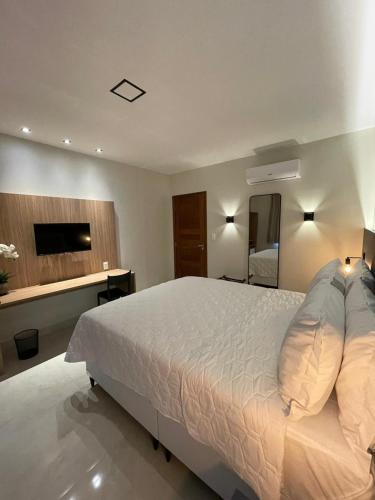 a bedroom with a large white bed and a television at Luster Hotel in João Câmara