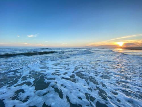 a beach with snow on it with the sun setting at Pet Friendly Beach vacay on a Budget in Bolivar Peninsula