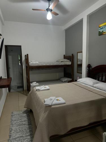 a bedroom with two beds and a ceiling fan at Suites Brejauva in Ubatuba