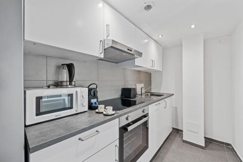 a white kitchen with a microwave and a sink at K22 Smart Rooms in Vienna