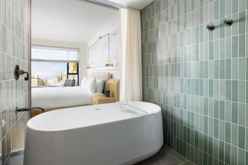 a bathroom with a bath tub and a bedroom at Timbri Hotel San Francisco, Curio Collection by Hilton in San Francisco