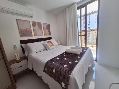 a bedroom with a bed and a large window at Apartamento luxo, pertinho do Mar e lazer maravilhoso in Vila Velha
